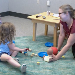 woman interacts with young child in autism research lab